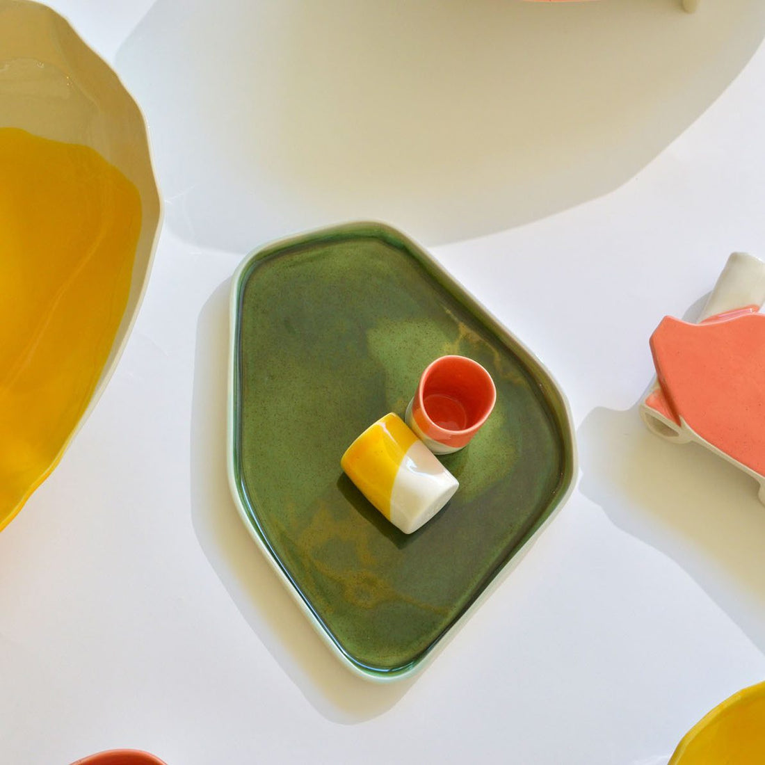 Kiwi Green porcelain serving tray holding small yellow and orange cups among colourful tableware