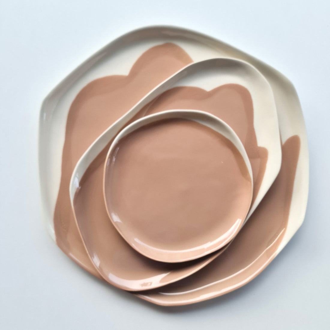 Nested handmade porcelain plates in Mocha Mousse glaze with irregular white rims, seen from above