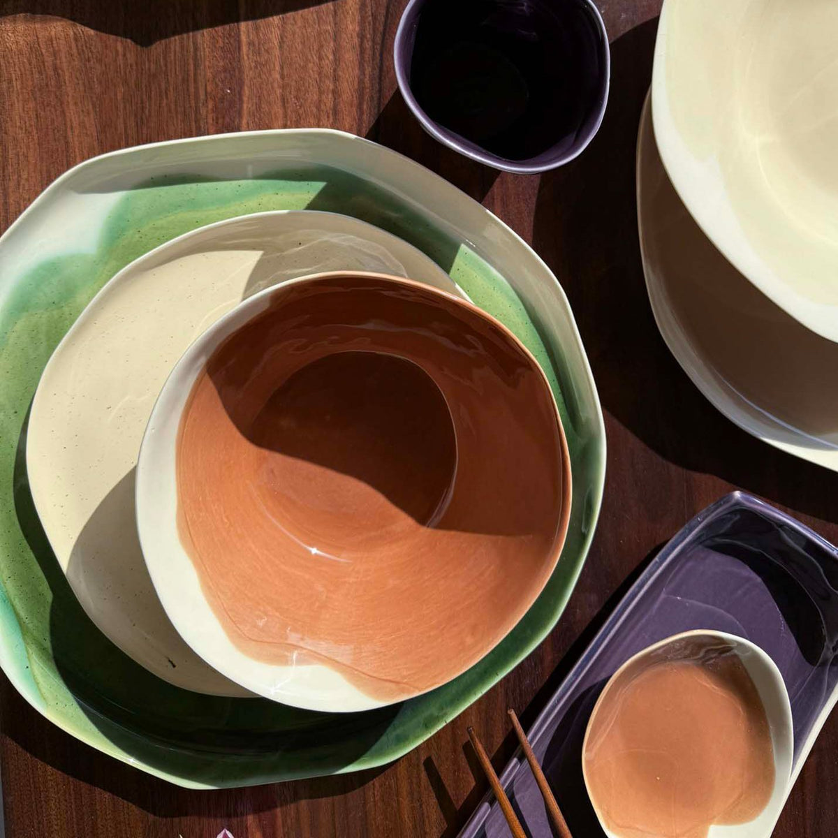 Hazelnut porcelain bowl nested on green and white plates, with a small dish and chopsticks