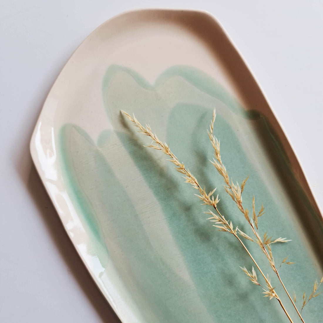 Handmade porcelain serving platter with Sage Green glaze brushstrokes and a sprig of dried grass