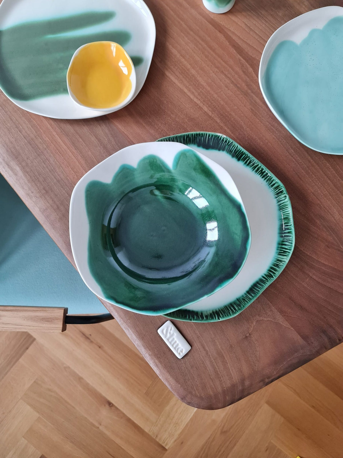 Handmade ceramic dinnerware in Forest Green and turquoise glaze on a walnut dining table