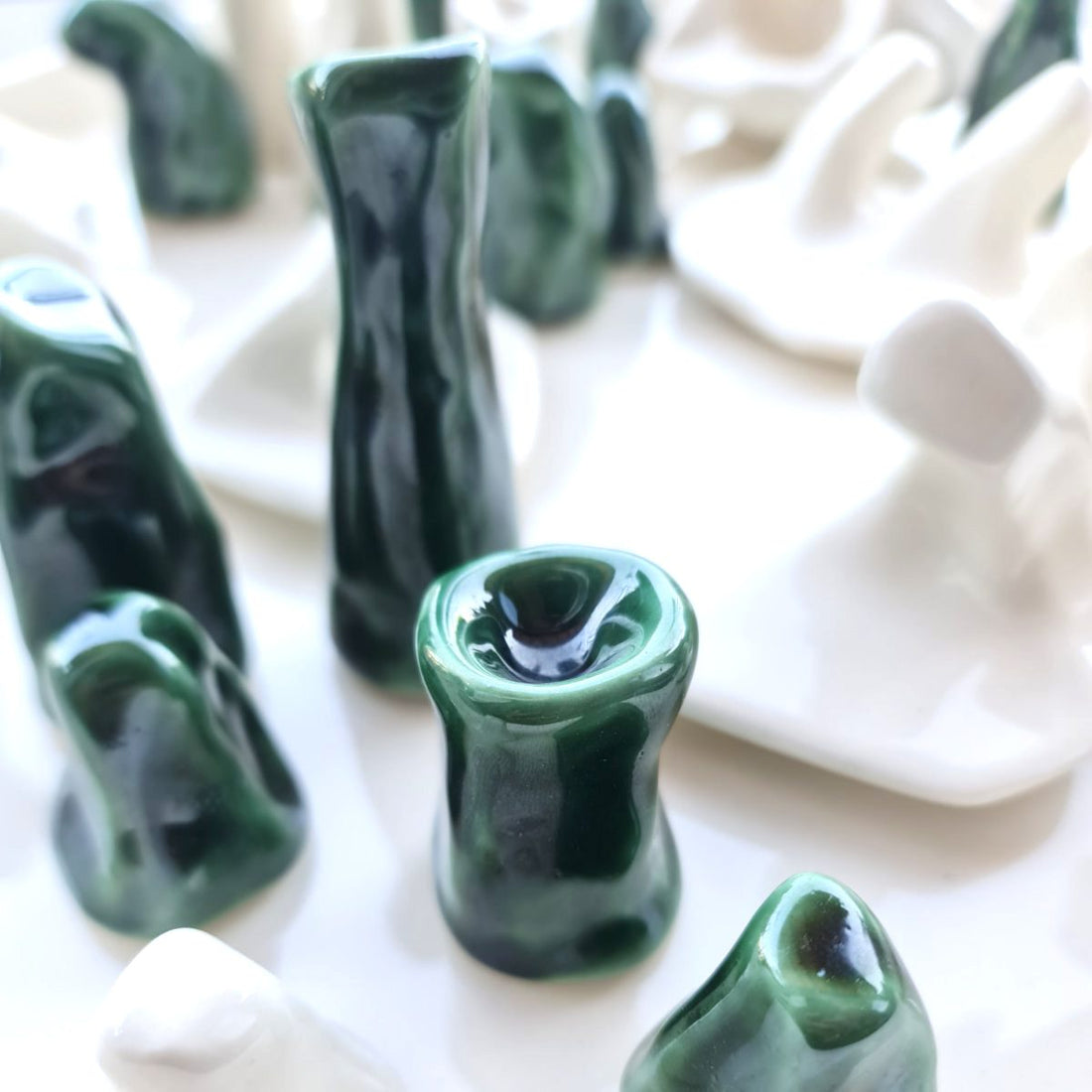 Handmade porcelain candle holders in glossy Forest Green glaze among white sculptural ceramics