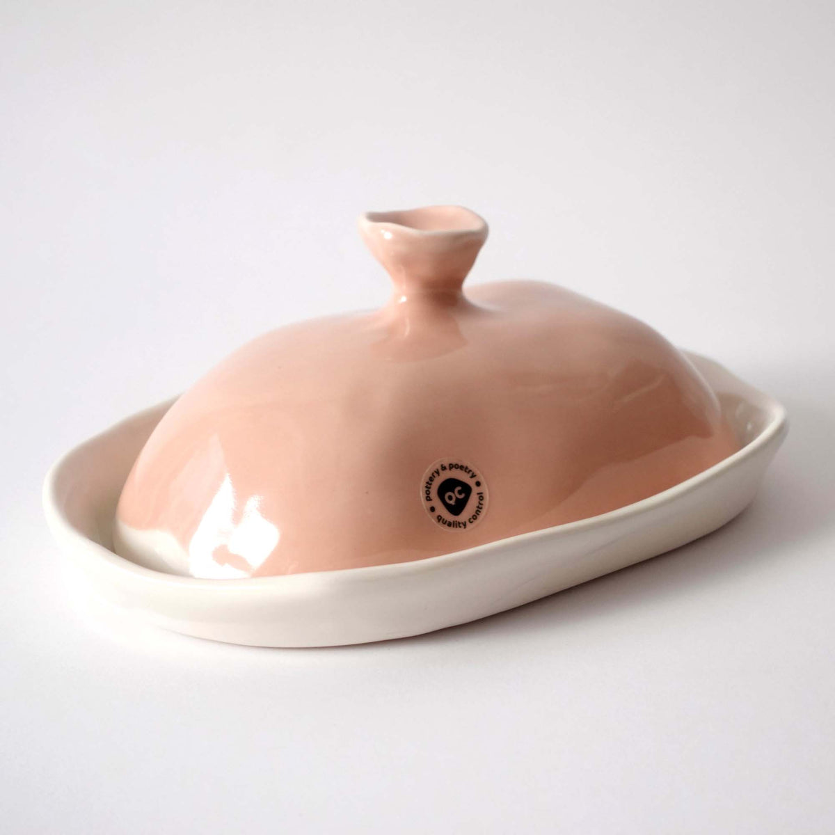 Handmade porcelain butter dish with a Milky Pink domed lid and sculpted knob on a white tray