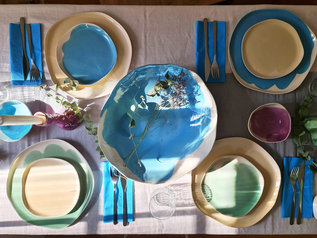 Dinner table from above set with Sky Blue and blue handmade ceramic plates and blue cutlery