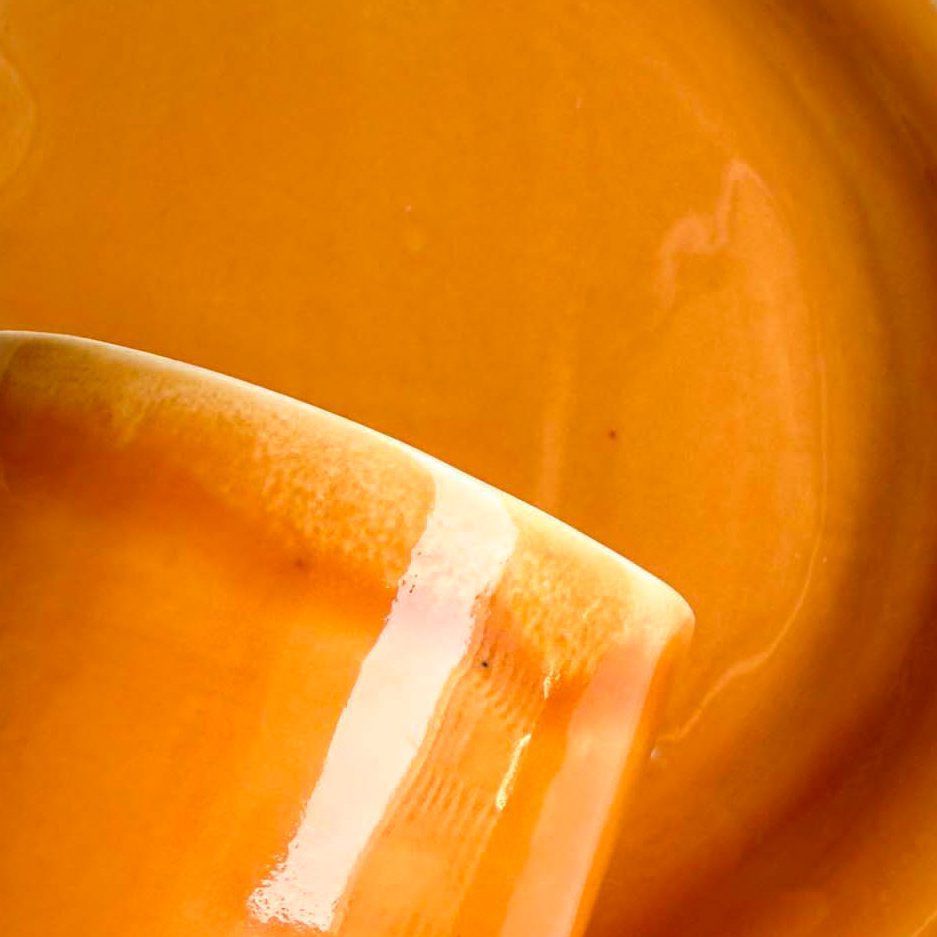 Saffron glossy glaze sample on handmade porcelain, with a white-dipped cup in close-up