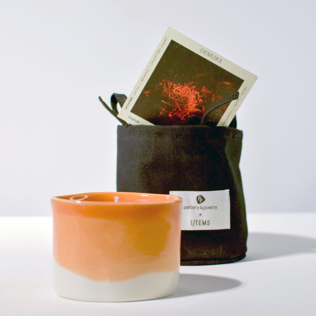 Peach-orange and white handmade porcelain cup beside a gift bag holding an inspiration card