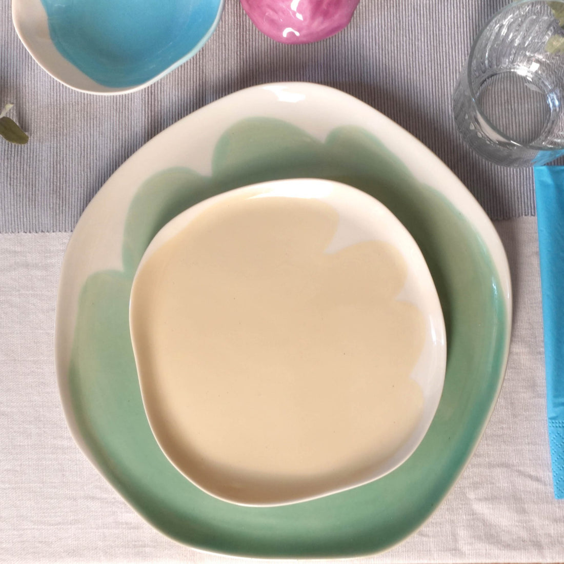 Ivory handmade porcelain plate on a larger sage green and white plate on linen
