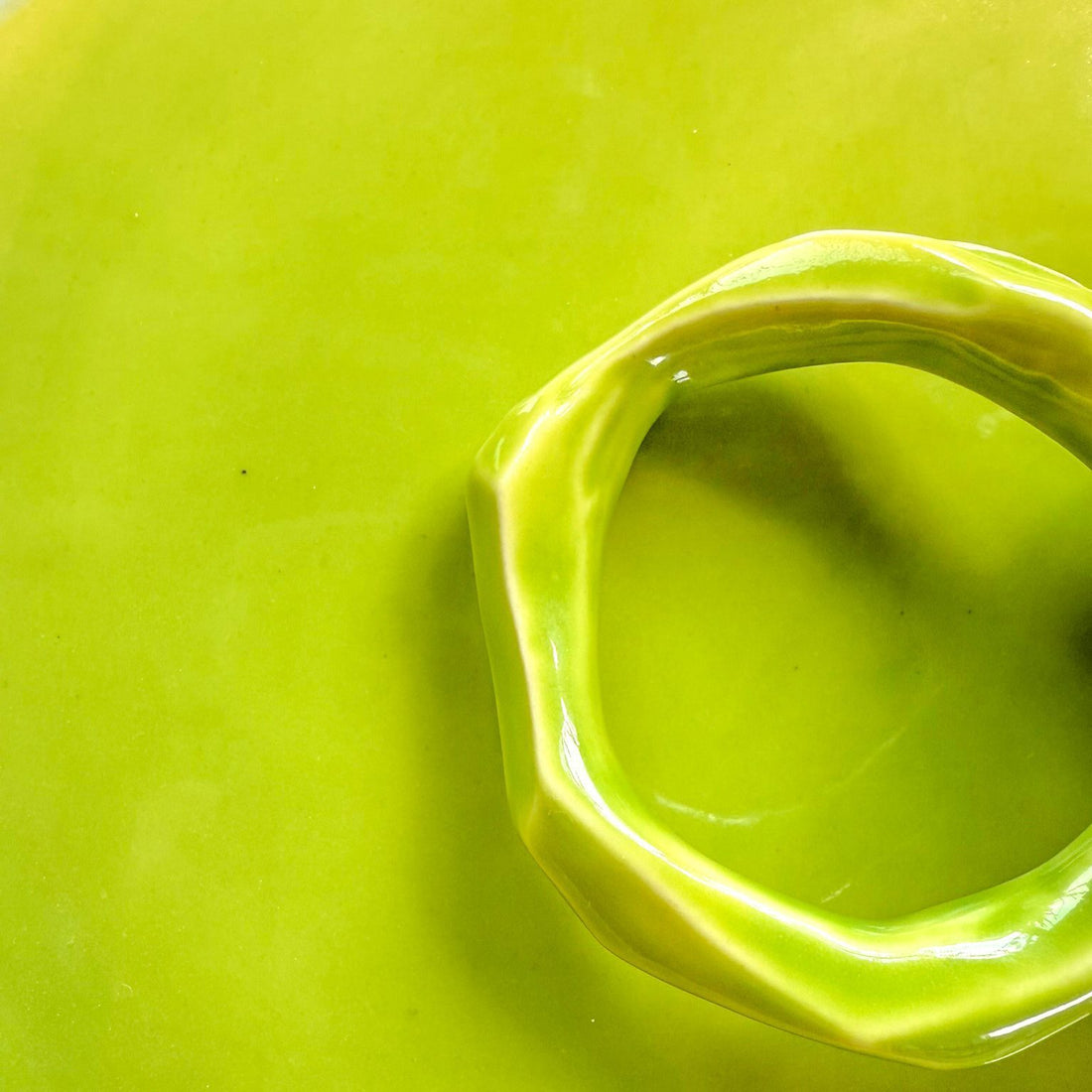 Lime glossy glaze sample on handmade porcelain with a sculpted organic handle in close-up