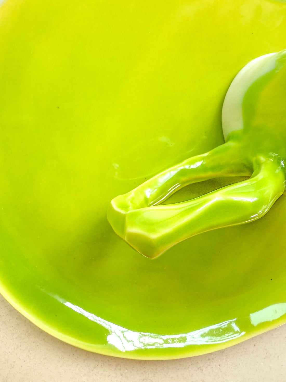 Close-up of a sculpted porcelain handle glazed in bright Lime on a matching Lime plate