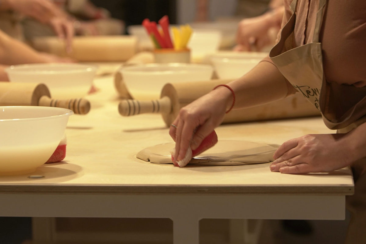 Guests rolling out clay slabs with wooden rolling pins during a ceramic workshop in Sofia
