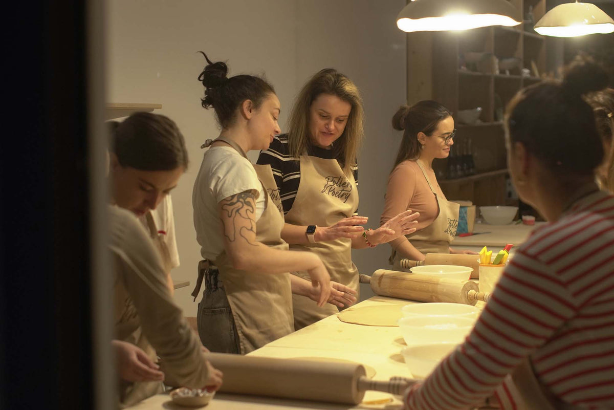 Workshop participants in aprons rolling clay at long tables in the Sofia ceramics studio