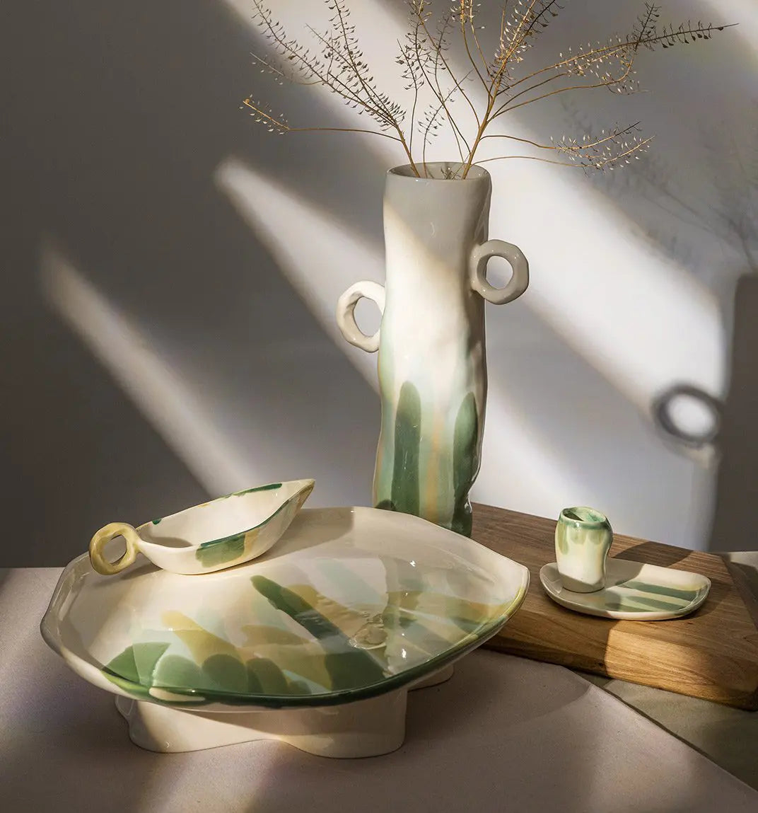 Handmade green-and-ivory ceramic vase, plates and cups with dried branches