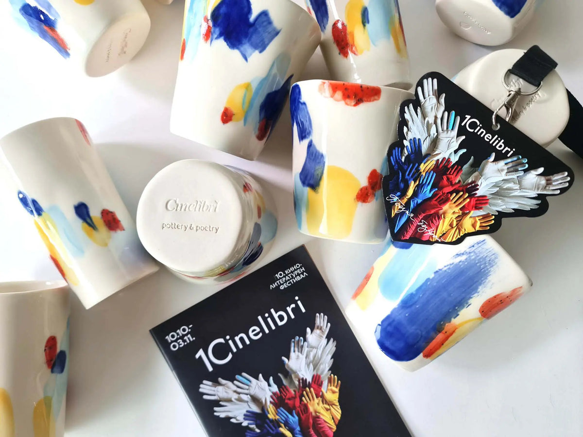 Branded porcelain cups with painted blue, red and yellow brushstrokes made as corporate gifts