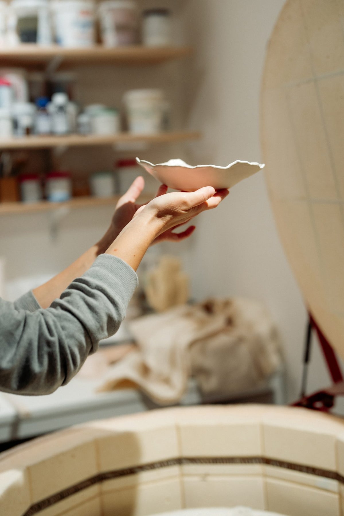 Hand raising a freshly made porcelain plate in the Pottery & Poetry studio in Sofia
