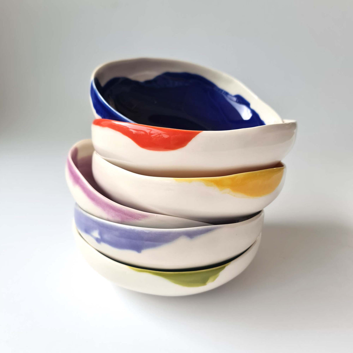 Stacked round bowls with a blue bowl on top and contrasting glazed rims