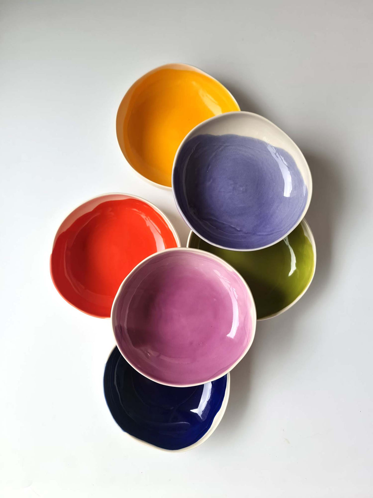 Colourful round handmade bowls arranged vertically and viewed from above