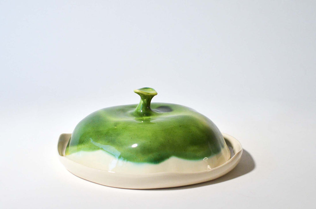 Round handmade ceramic cheese box with a glossy green lid and an ivory plate