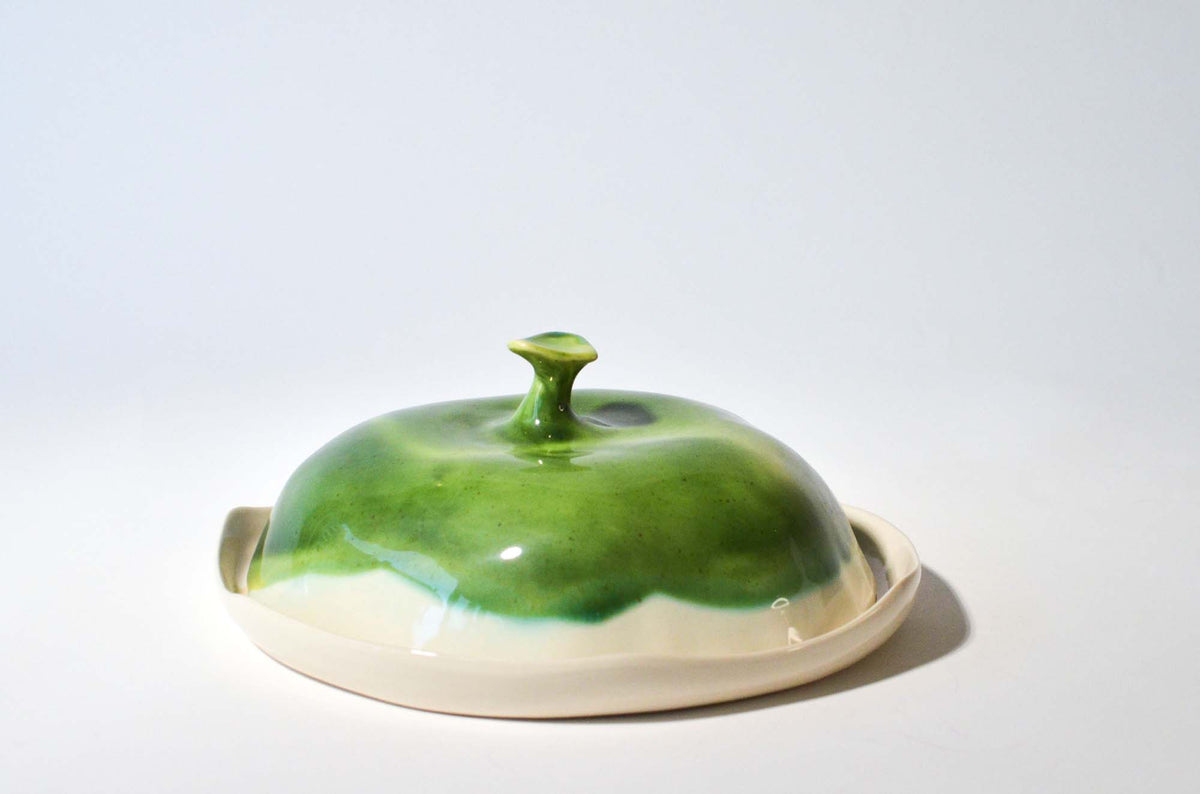 Round handmade ceramic cheese box with a glossy green lid and an ivory plate
