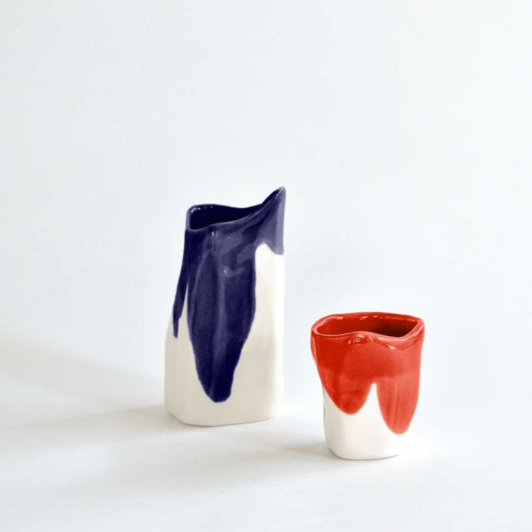 Handmade porcelain creamer in cobalt blue and a red coffee cup