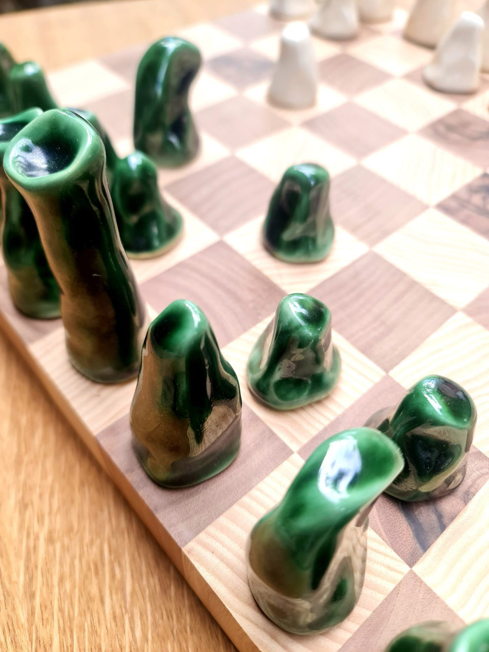Custom chess set with glossy green glazed porcelain pieces on a wooden board