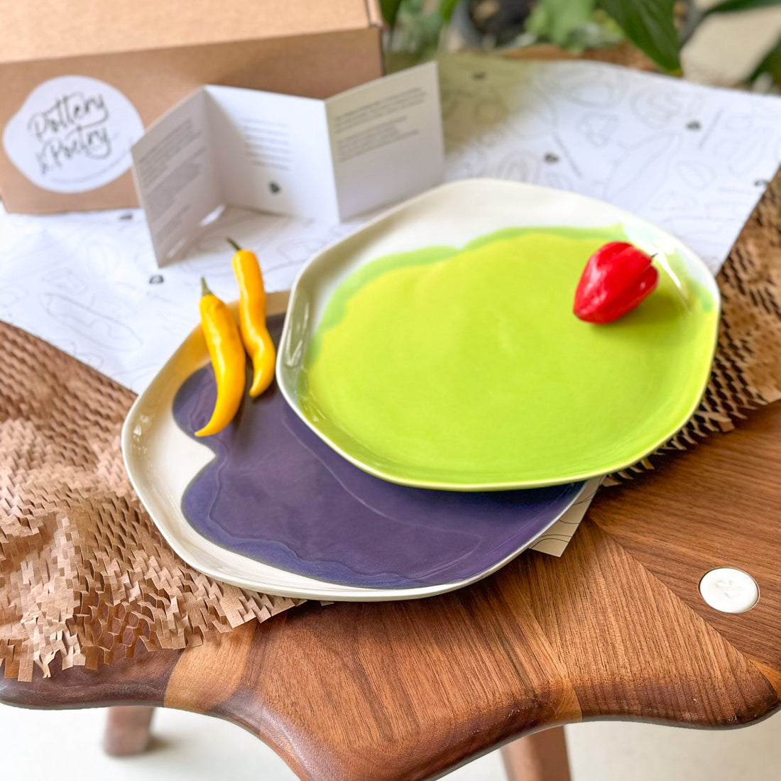 Green and purple handmade dinner plates beside a red pepper and bananas
