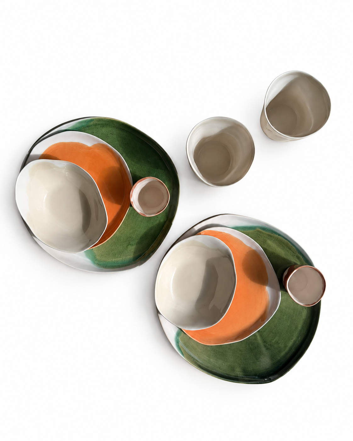 Overhead view of two ceramic place settings in olive green, orange and ivory