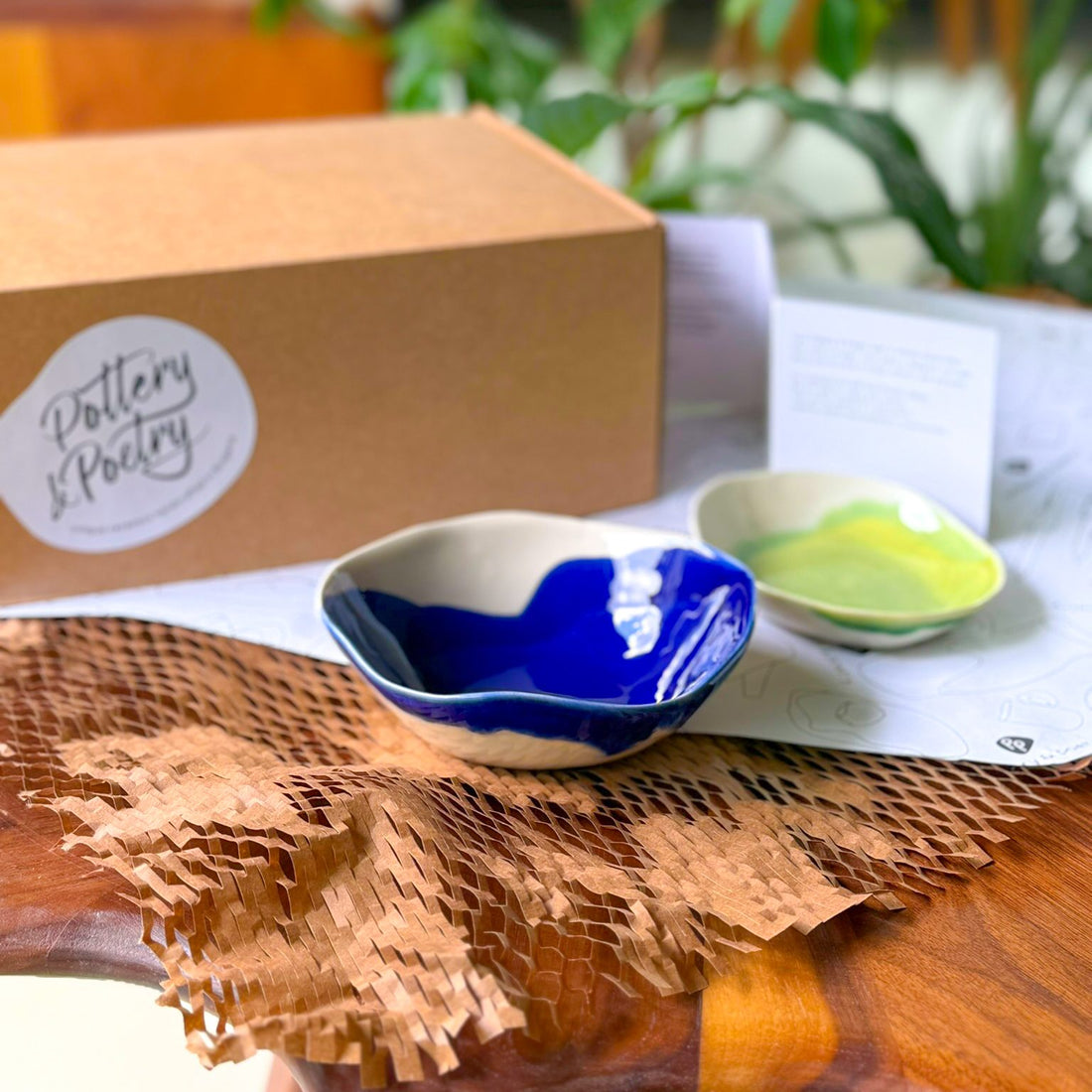 Two handmade dip bowls in cobalt blue and lime green glaze, unpacked from a Pottery & Poetry gift box