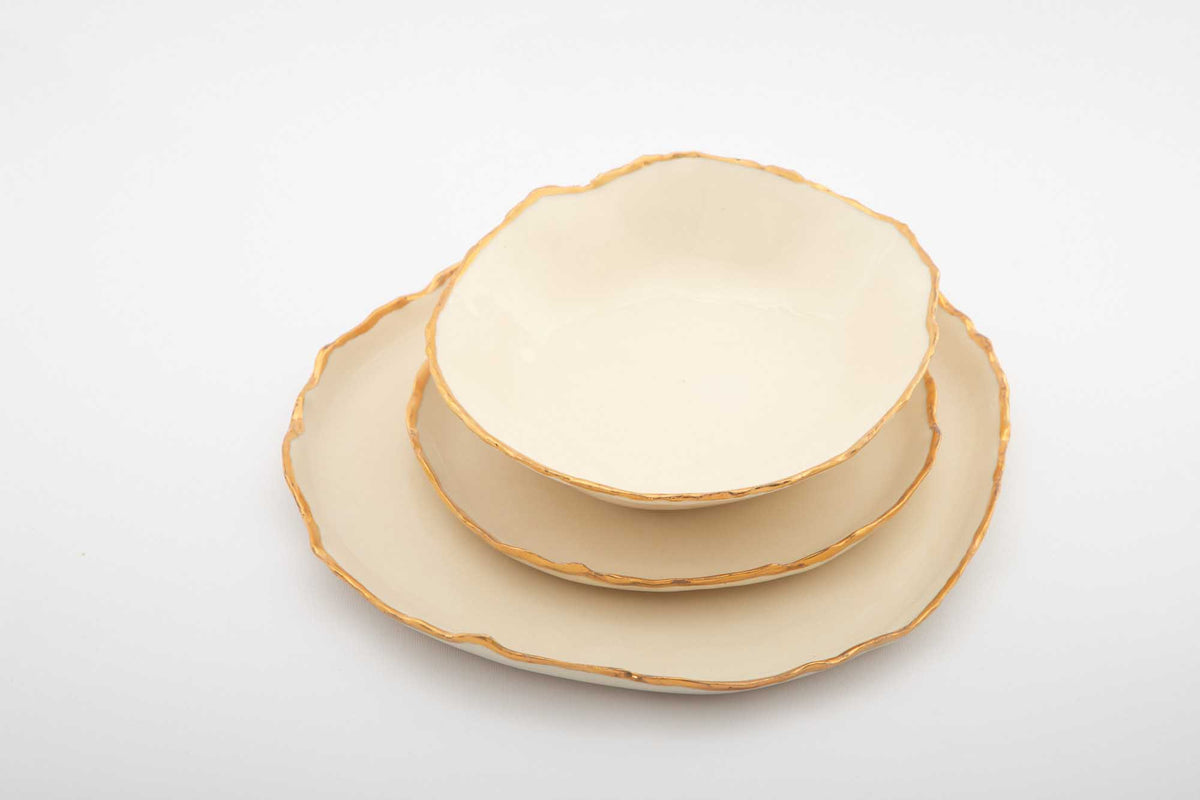 Ivory Gilded Ridges dining set showing the handmade bowl and gold-edged plates