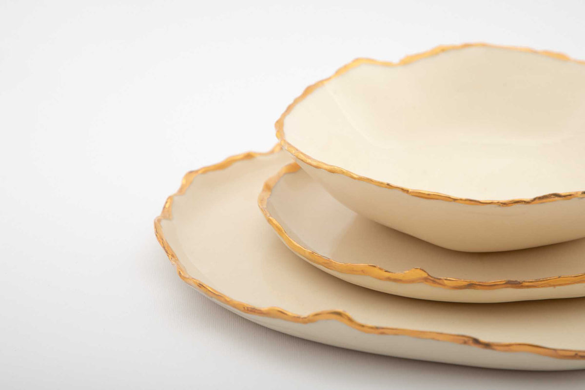 Close-up of an ivory Gilded Ridges bowl on gold-edged plates