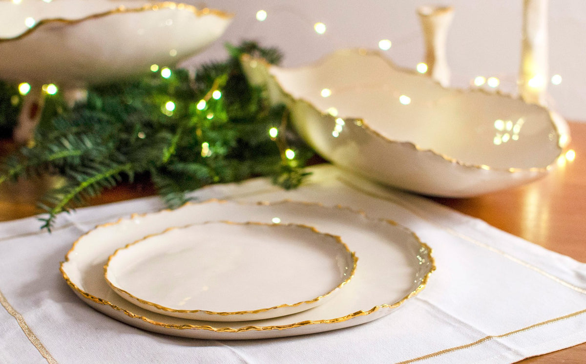 Gold-edged handmade ceramic plates and bowls in a festive table setting