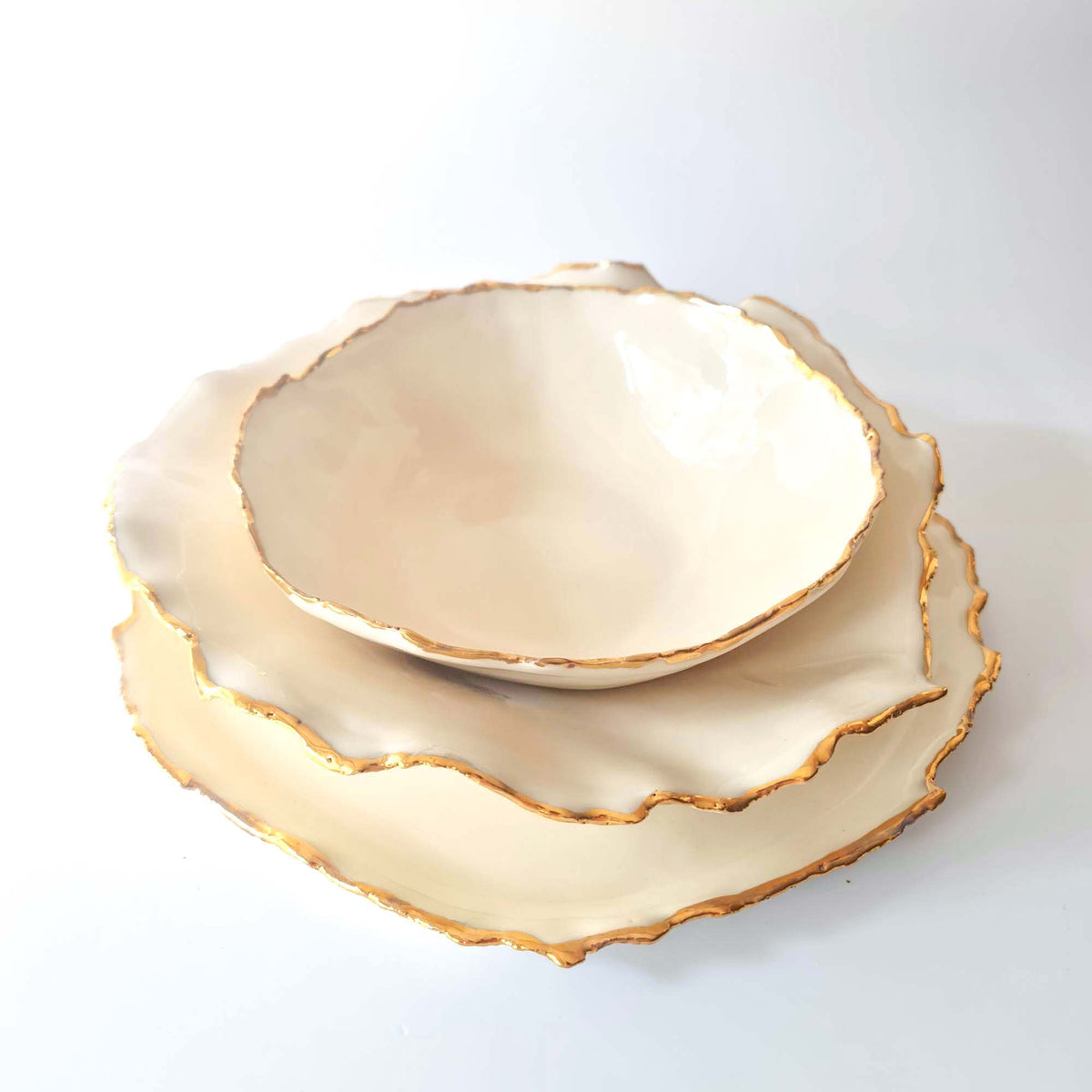 Top view of an ivory Gilded Ridges bowl and two gold-edged plates