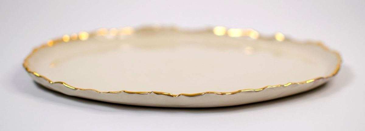 Ivory Gilded Ridges dinner plate with an irregular gold-finished rim, viewed from the side