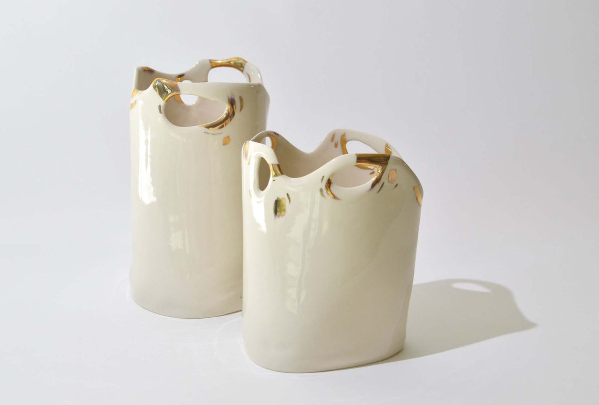 Two handmade white porcelain vases with torn gold-trimmed rims and cut-outs, from the Laced collection