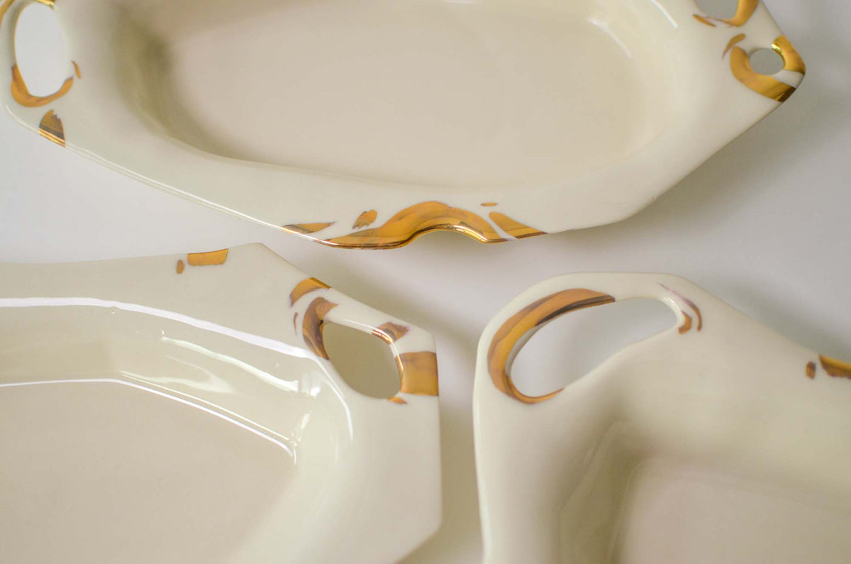 Close-up of Laced collection porcelain platters with open handles trimmed in gold