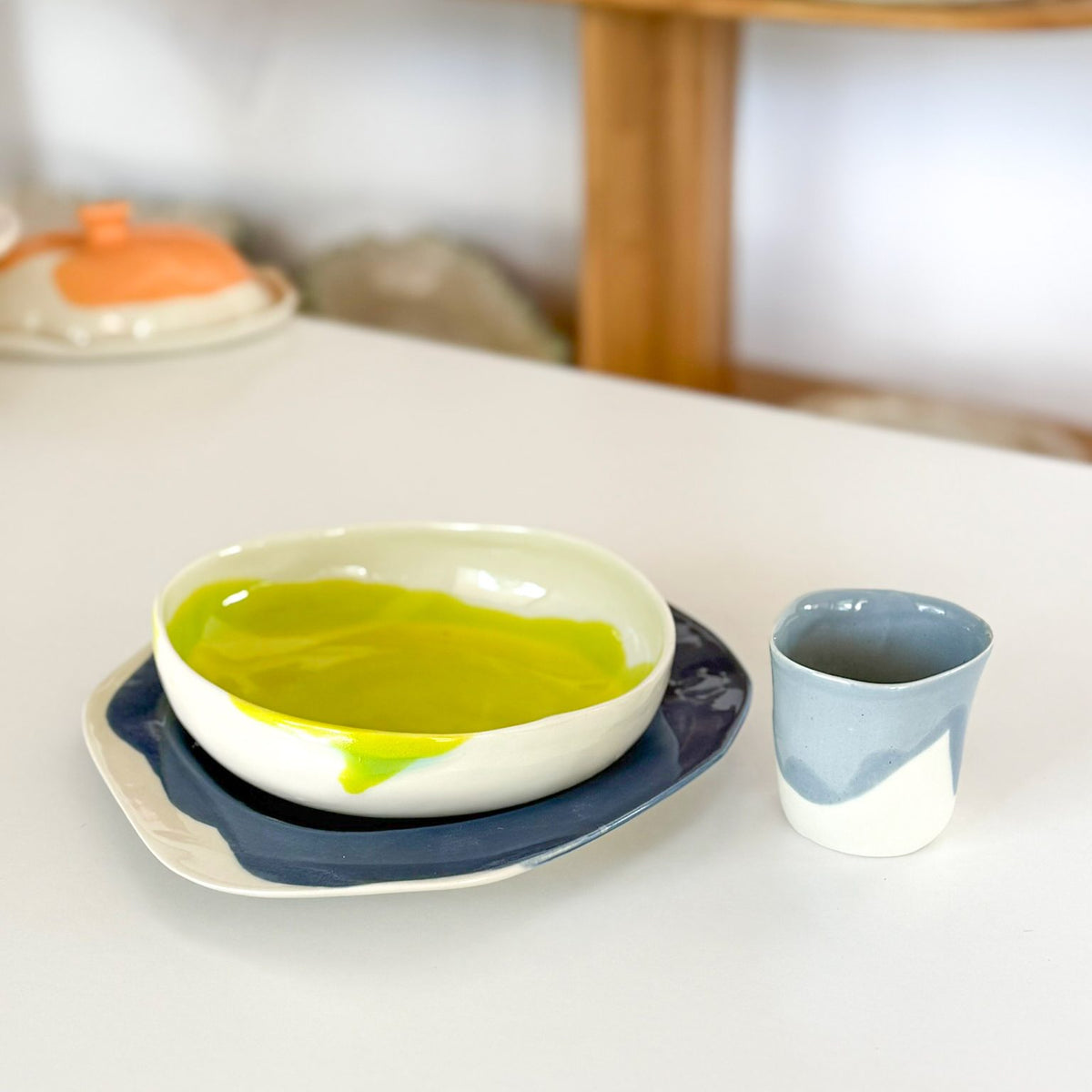 Handmade plate, green bowl and blue cup arranged as a child's place setting