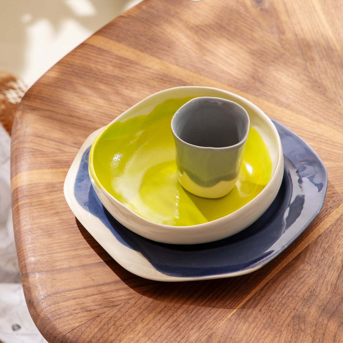Ceramic child's place setting with a green bowl and cup on stacked plates