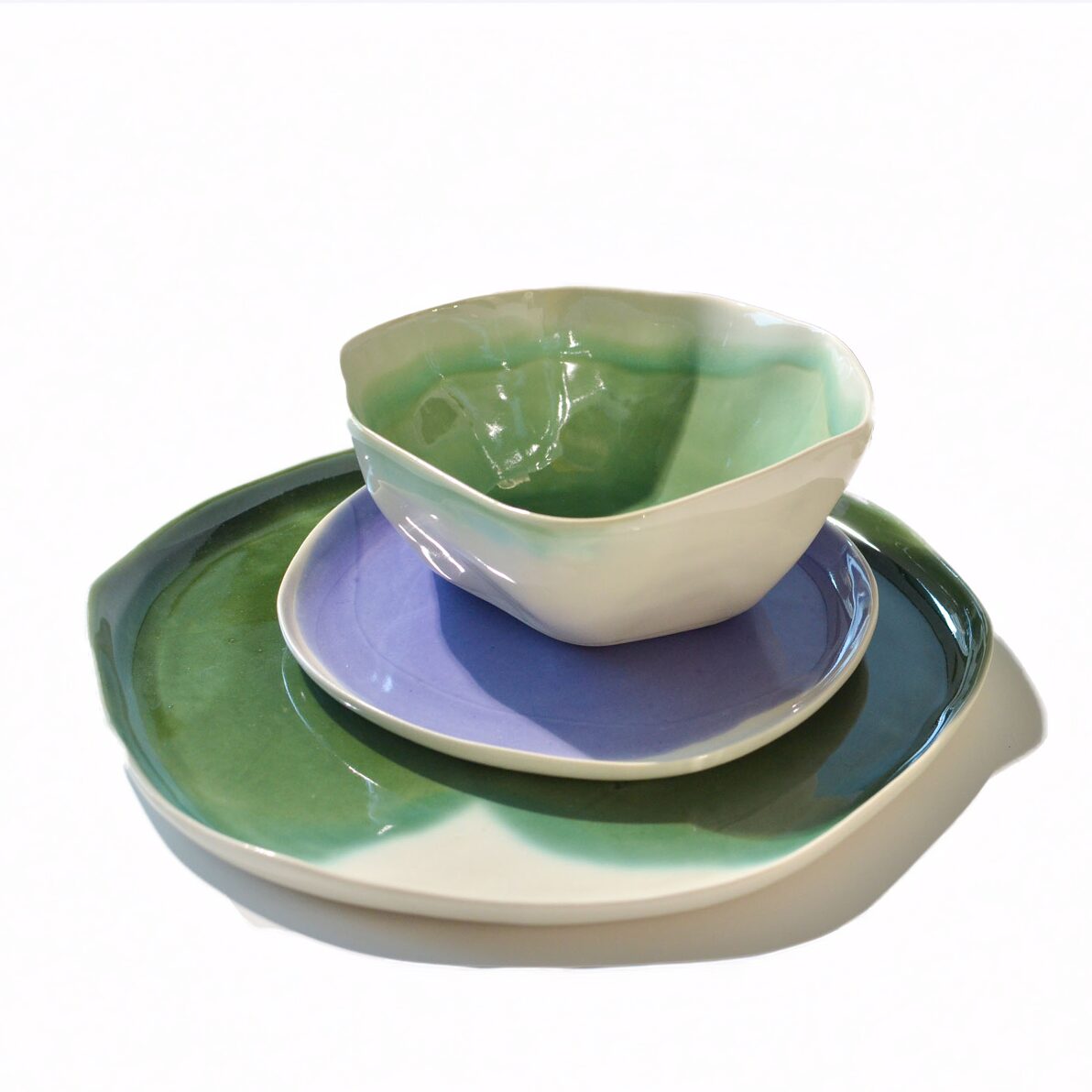 Green ceramic bowl on stacked lavender and green plates