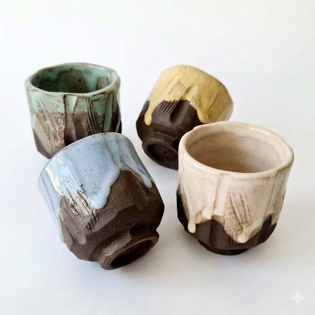 Four kurinuki specialty coffee cups carved from dark clay with running glaze
