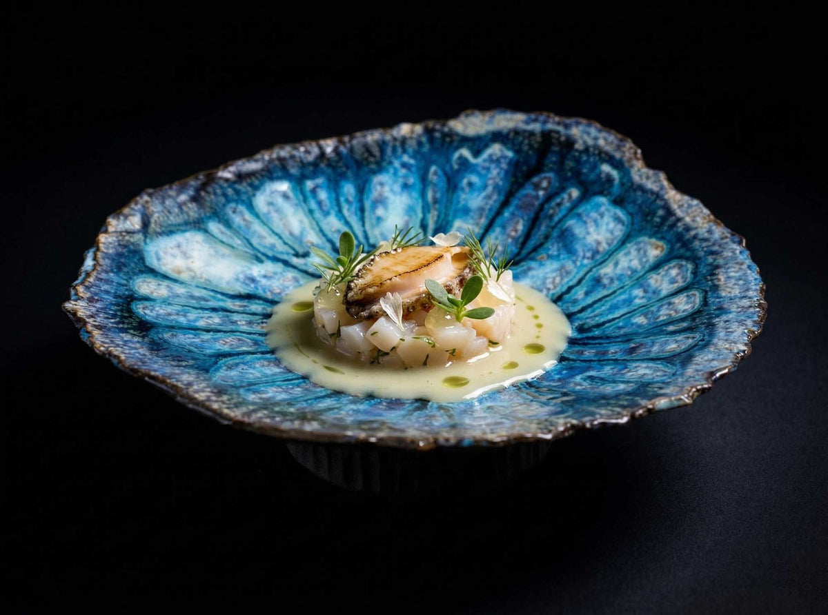 Legged Plate from Black Clay with a blue glazed well, holding a fine dining seafood dish