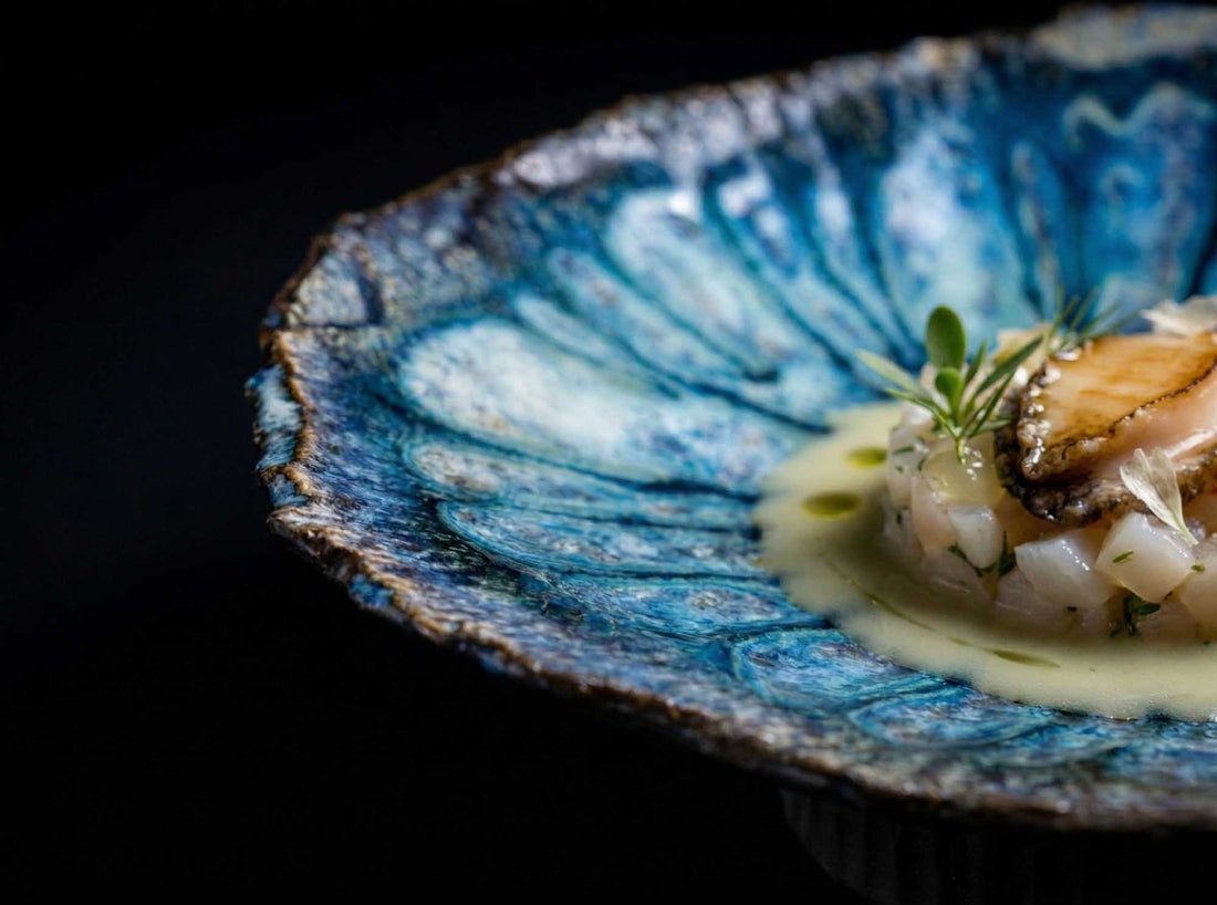 Legged Plate from Black Clay with reactive blue glaze, serving a fine dining seafood dish