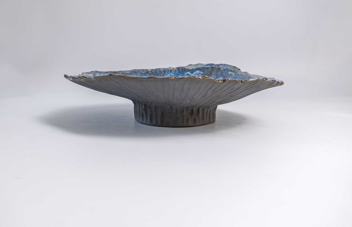 Side view of the Legged Plate from Black Clay showing its raised foot and wide flared rim