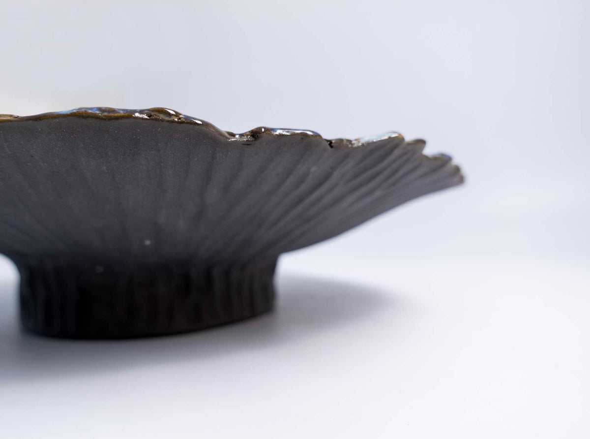 Low side view of the Legged Plate from Black Clay revealing the fluted matte black foot