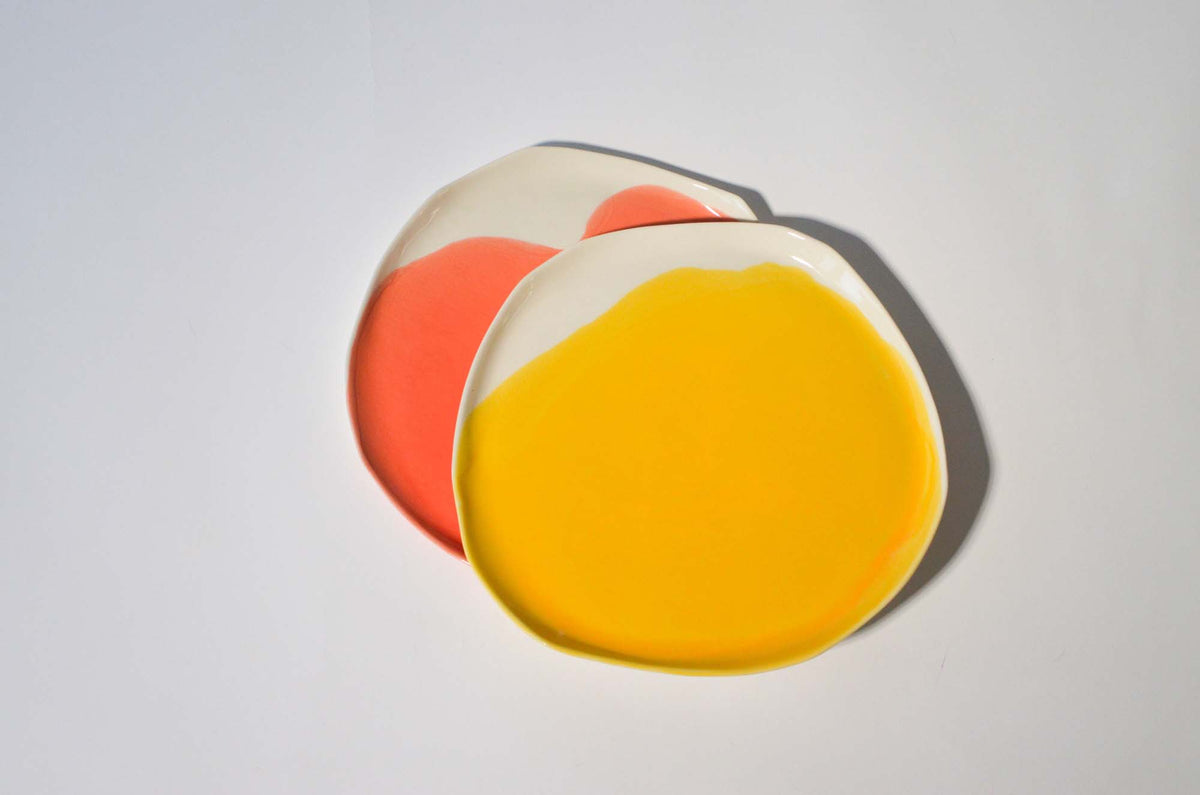 Yellow, red and ivory handmade dinner plates overlapping on a white background