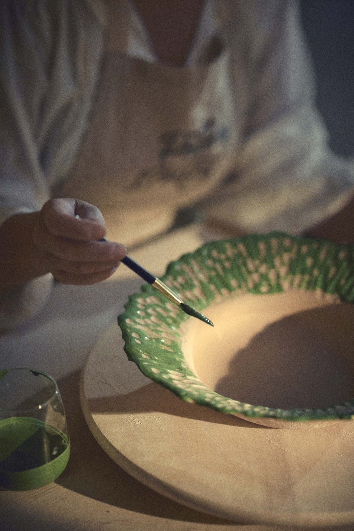 Green glaze brushed by hand onto the textured rim in the Pottery & Poetry studio