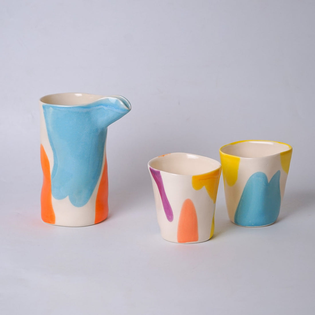 Multicolour ceramic coffee set with a jug and cups glazed in blue, pink and yellow