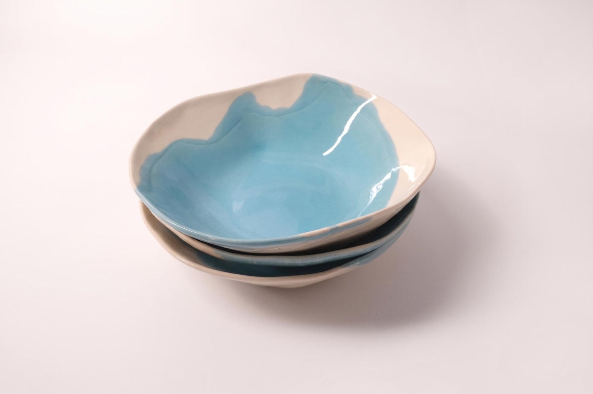 Nested handmade bowls in Sky Blue glaze on a pale-pink background