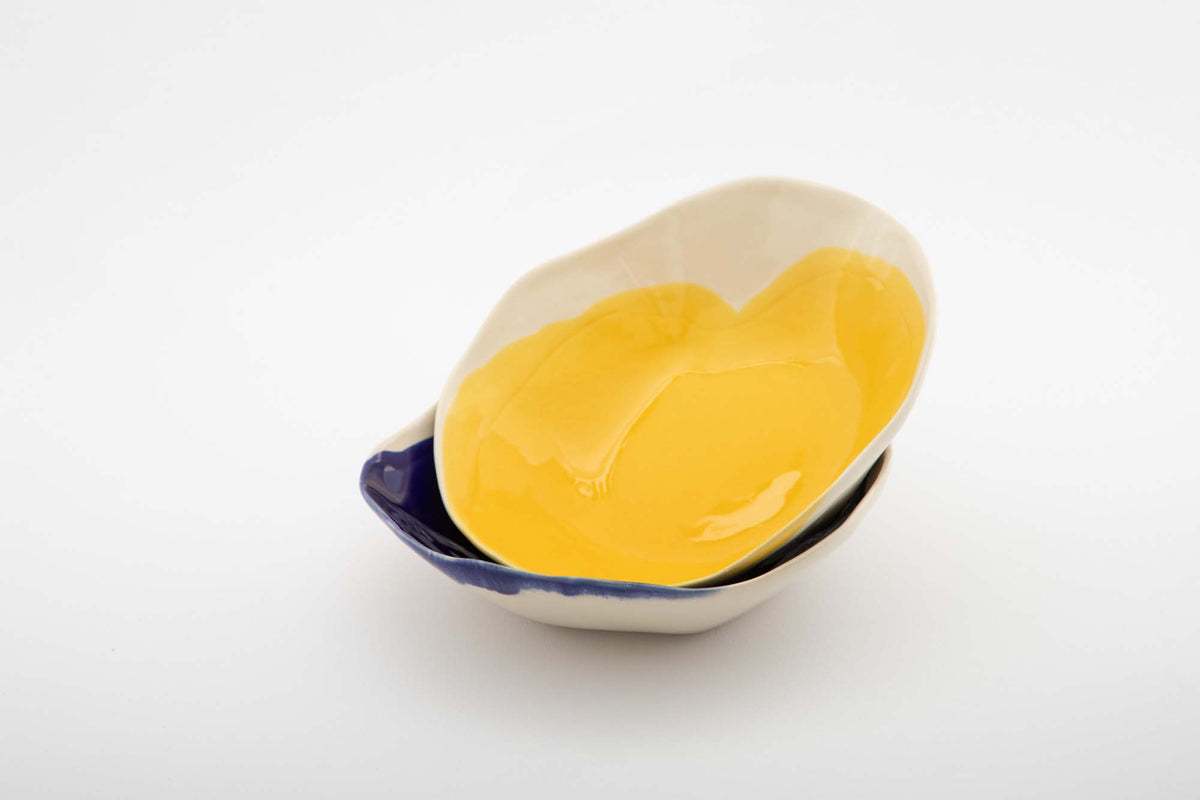 Yellow handmade ceramic bowl with an irregular ivory rim, nested with other bowls