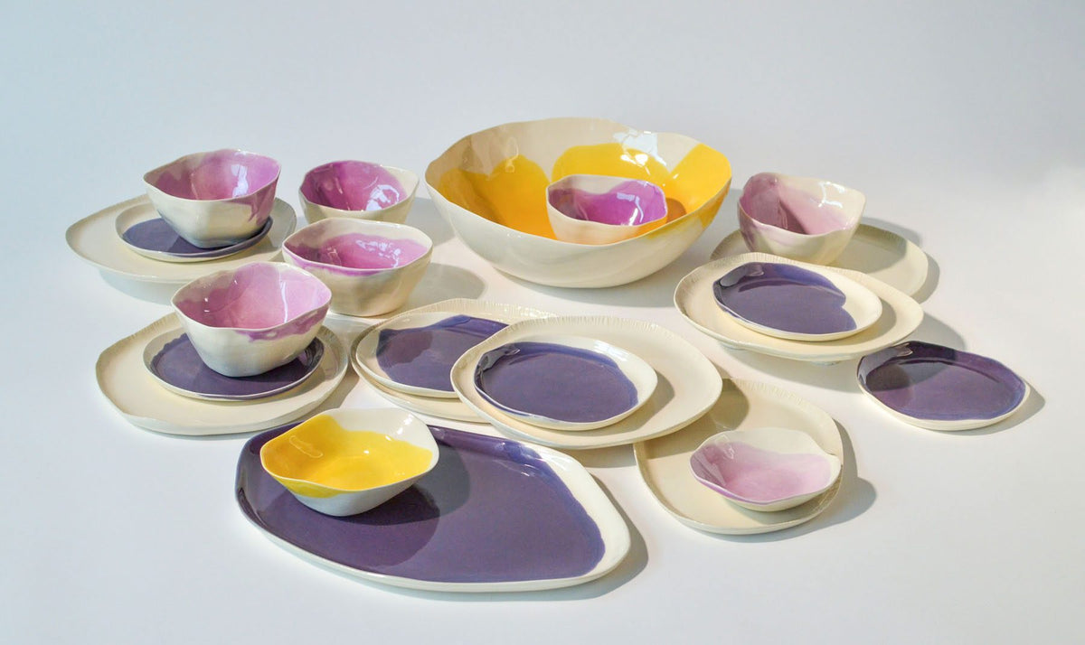 Customizable dining set for 4 in lavender, pink and yellow glazes, plates and bowls laid out