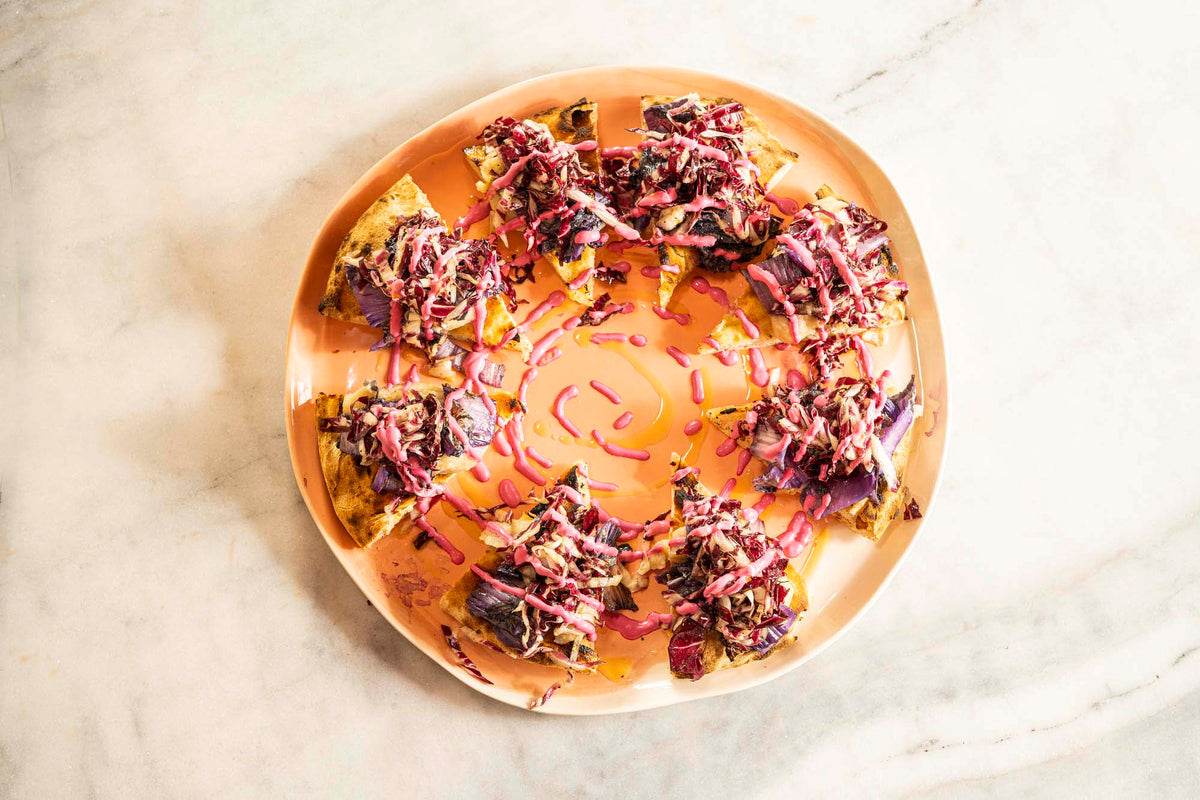 Pizza topped with purple cabbage on a handmade ceramic plate