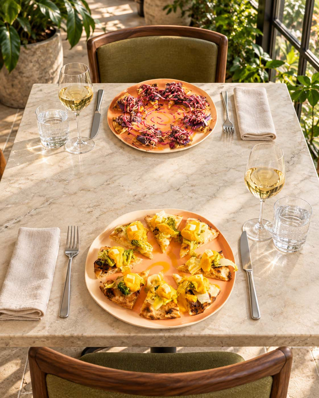 Two pizzas served on handmade ceramic plates at an outdoor table